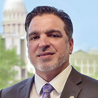 A person smiling for the camera Description automatically generated with low confidence